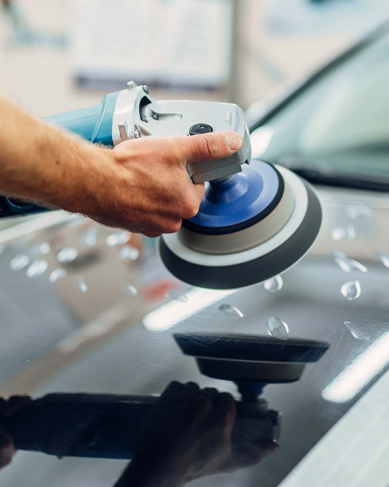 worker-with-polishing-machine-cleans-car-hood-MYFCBD9.jpg